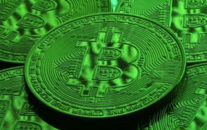 Close-up of a Bitcoin coin resting on a pile of other coins, the whole image tinted bright green.