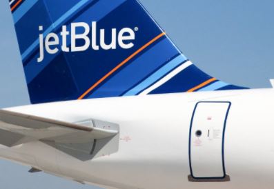 The tail and rear fuselage of a JetBlue aircraft on the tarmac, showing the blue tailfin and the jetBlue wordmark.